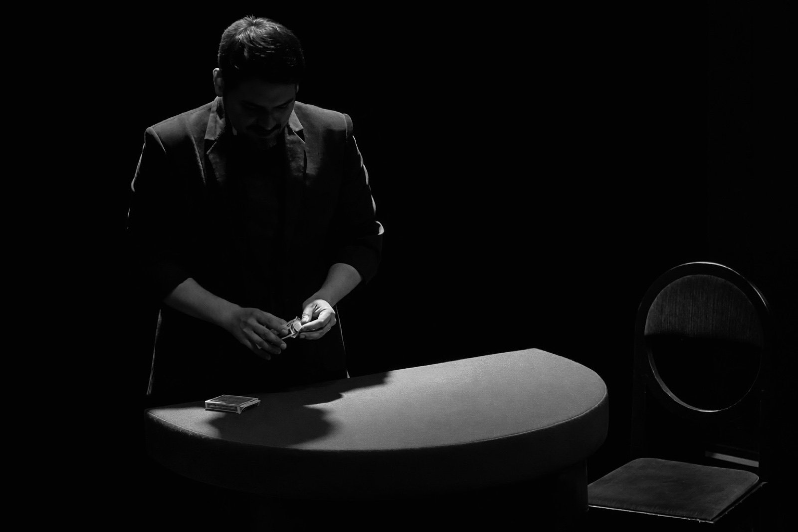Alejandro performing sleight of hand under a dramatic spotlight